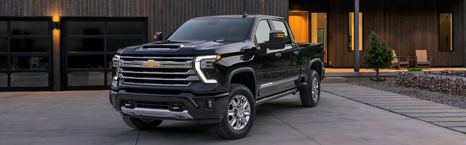 Black Chevrolet Silverado 2500 parked outside modern home.